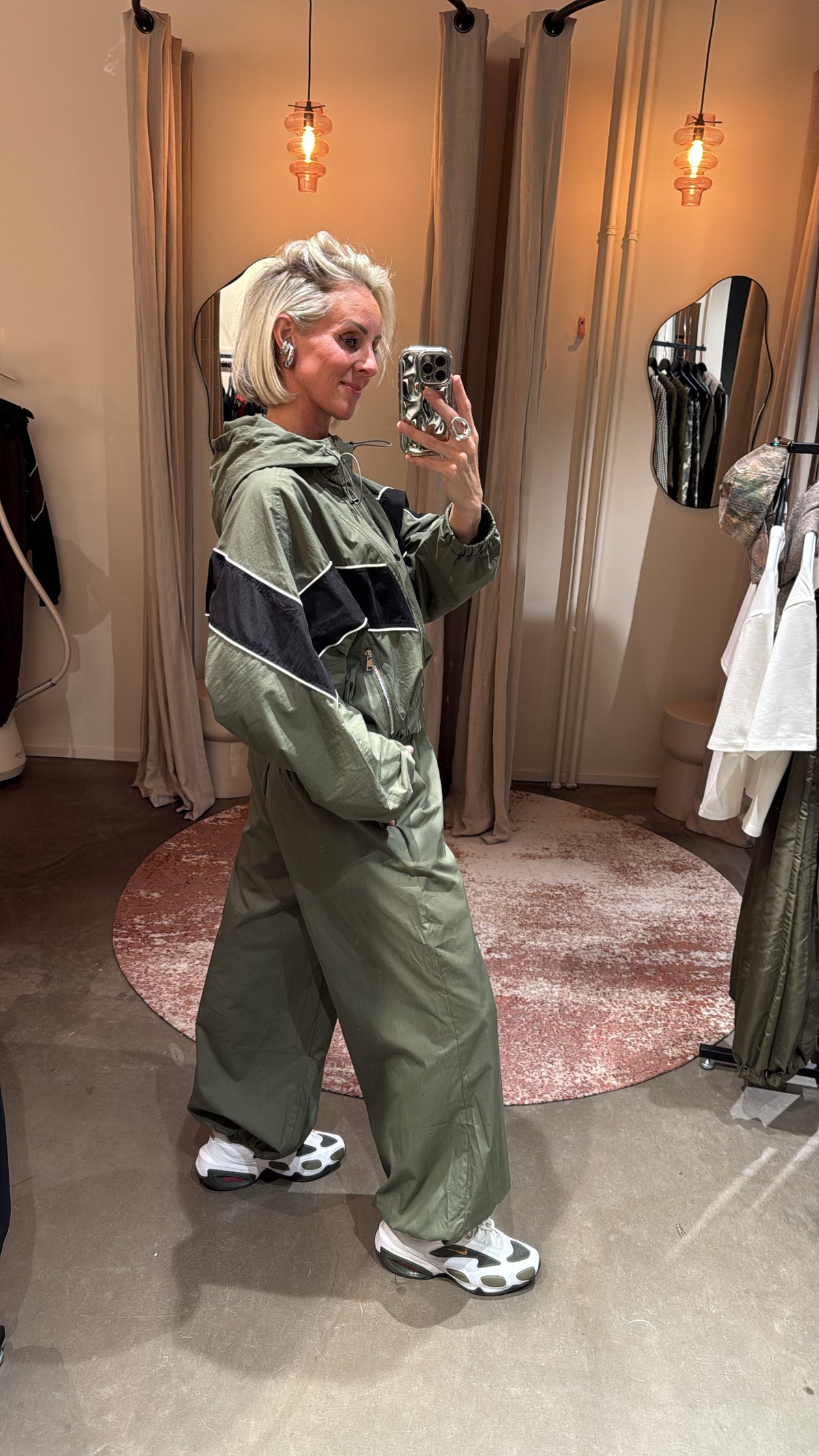 model draagt sporty track jacket green/black, zijaanzicht in paskamer