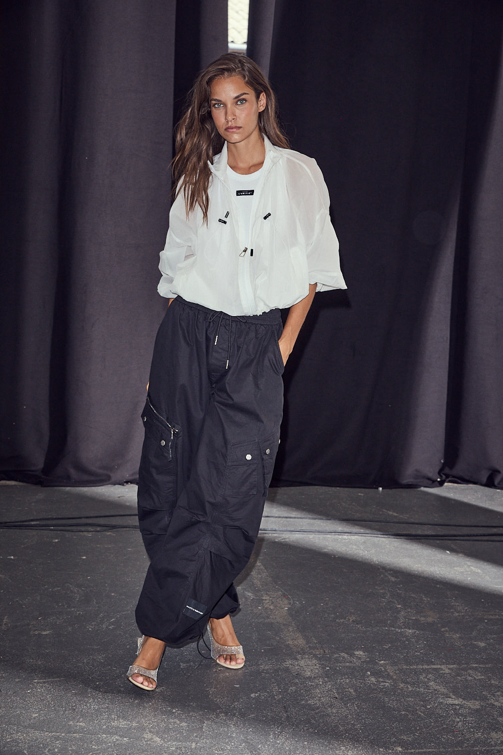 model draagt iron paper jacket white van haute l'amitié met zwarte cargobroek, volledige look