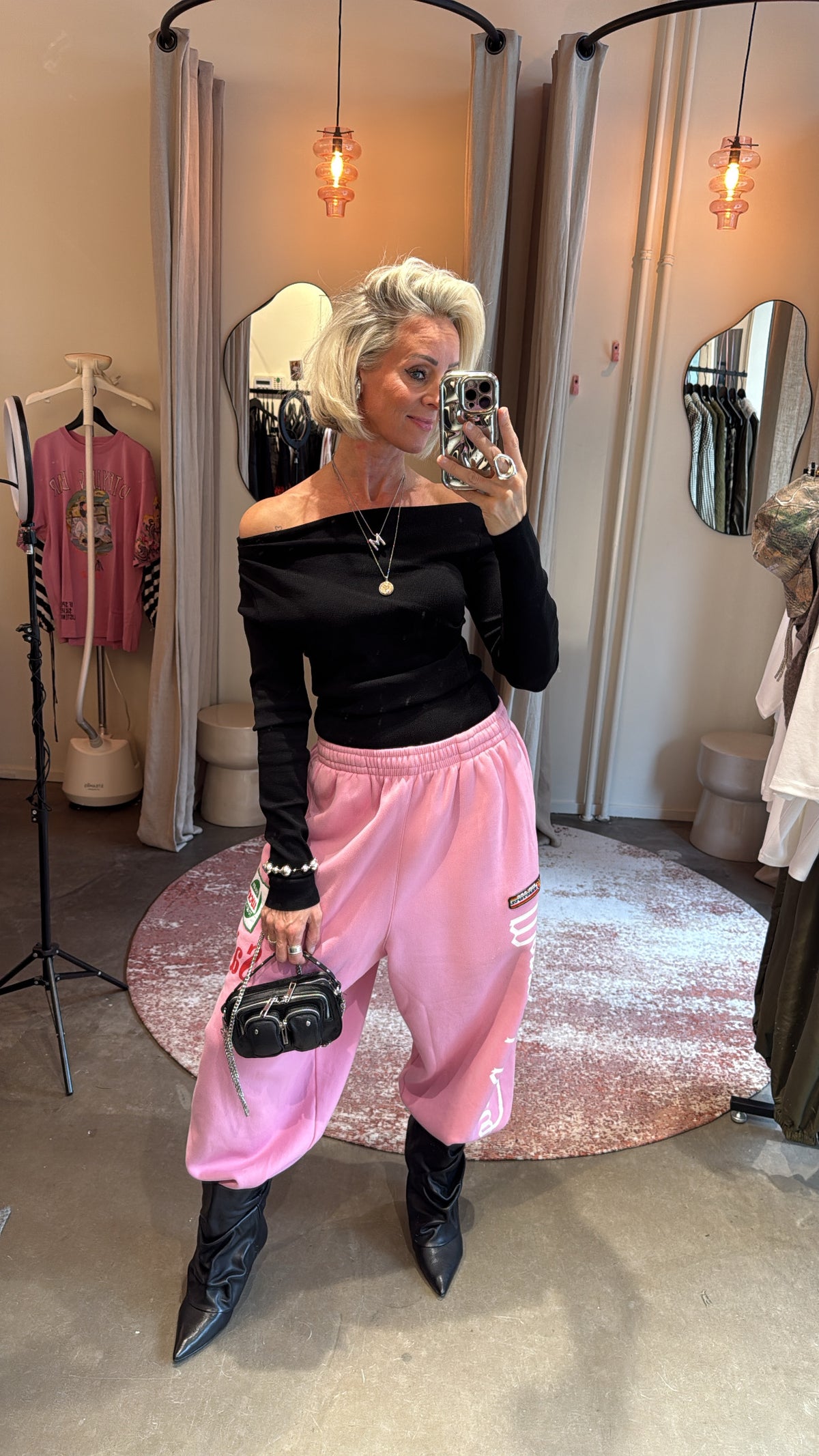 model draagt off shoulder top black van studio collection met roze joggingbroek, spiegelselfie