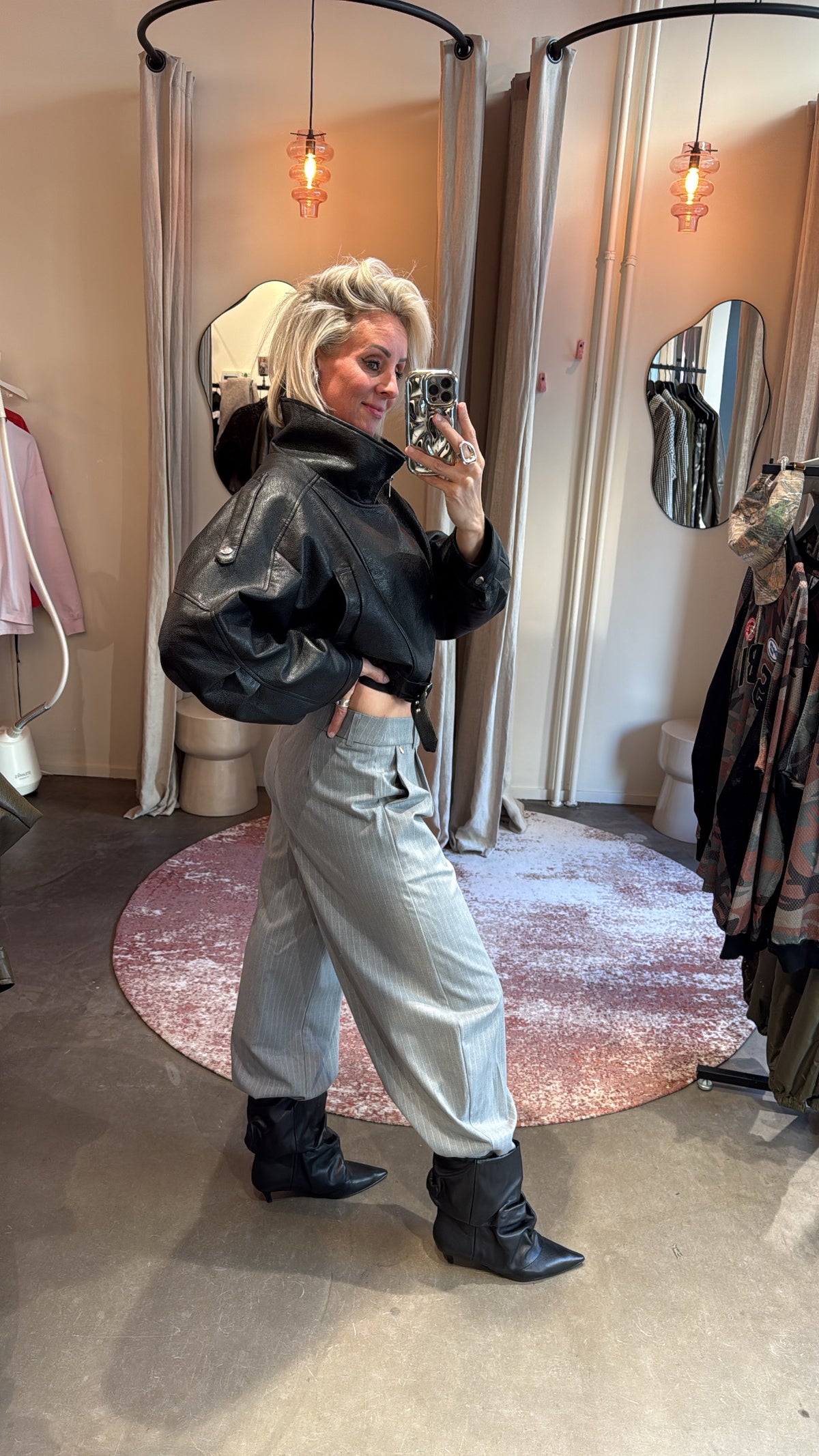 zijaanzicht van model in grijze pinstripe balloon pants met enkellaarsjes