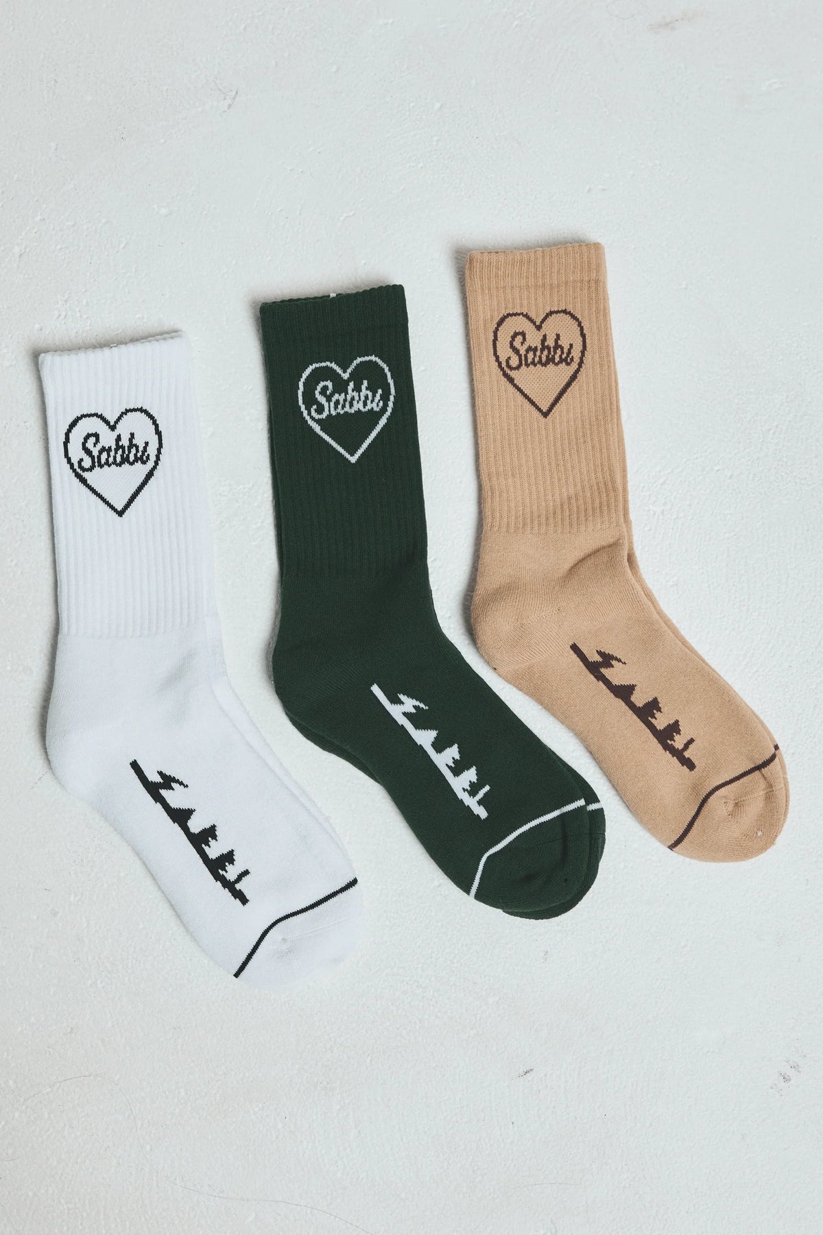 the sole mates sock 3 pack van sabbi in wit, groen en zand, flatlay met hartlogo en detail onder de voet