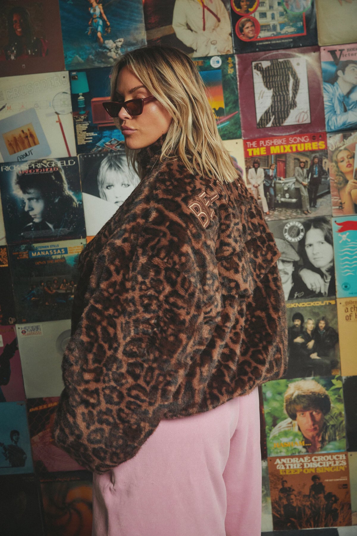 model van opzij in oversized leopardprint jas met geborduurde tekst op de schouder